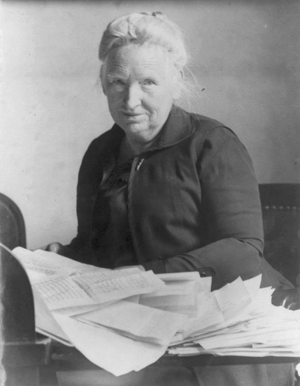 Photograph of Alice Robertson in old age, seated with papers on a table in front of her.